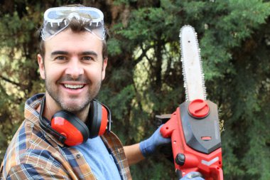 Ormanda testereyle ağaç kesen adam.