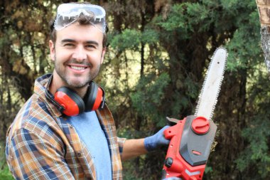 Ormanda testereyle ağaç kesen adam.