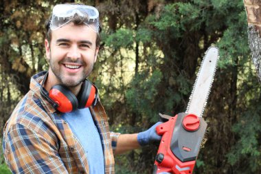 Ormanda testereyle ağaç kesen adam.