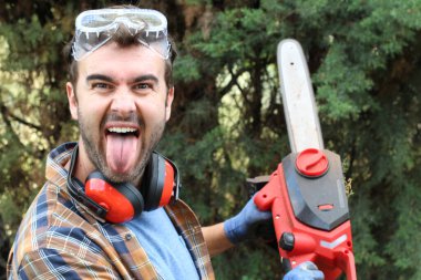 Ormanda testereyle ağaç kesen adam.