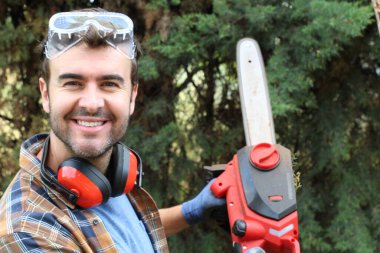 Ormanda testereyle ağaç kesen adam.