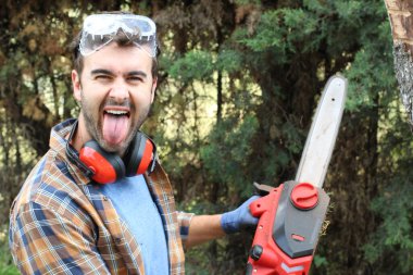 Ormanda testereyle ağaç kesen adam.