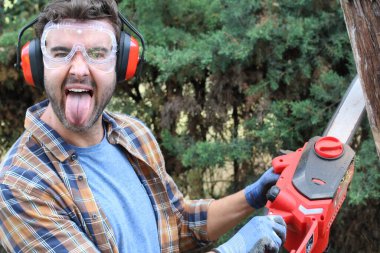 Ormanda testereyle ağaç kesen adam.