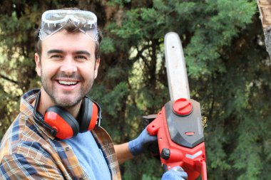 Ormanda testereyle ağaç kesen adam.