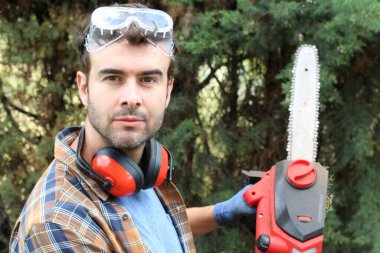 Ormanda testereyle ağaç kesen adam.