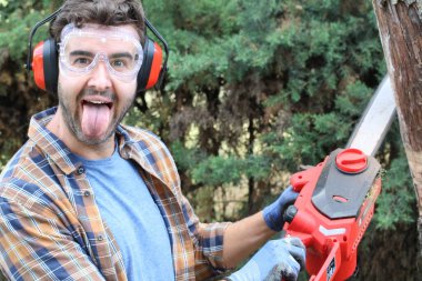 Ormanda testereyle ağaç kesen adam.