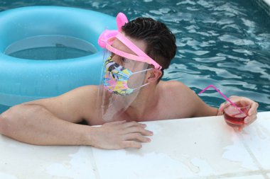 Coronavirus tecridi sırasında yüzme havuzunda tıbbi koruyucu maskeli yakışıklı genç adamın yakın plan portresi.