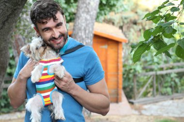 Yakışıklı bir delikanlının sokakta küçük şirin bir köpek yavrusuyla yakın plan portresi.