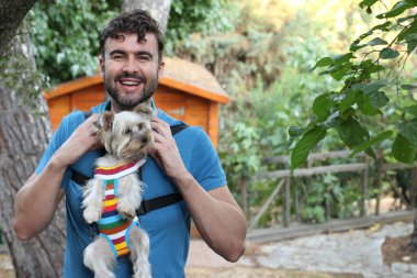 Yakışıklı bir delikanlının sokakta küçük şirin bir köpek yavrusuyla yakın plan portresi.