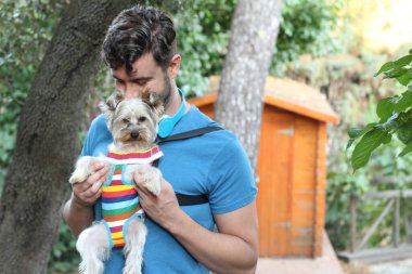 Yakışıklı bir delikanlının sokakta küçük şirin bir köpek yavrusuyla yakın plan portresi.