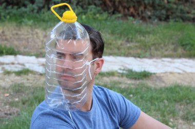 Yeşil Park 'ta tıbbi maske yerine plastik şişeli yakışıklı bir gencin yakın plan portresi. Komedi anlayışı.