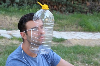 Yeşil Park 'ta tıbbi maske yerine plastik şişeli yakışıklı bir gencin yakın plan portresi. Komedi anlayışı.