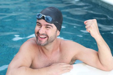 Yüzme gözlüklü ve havuzda lastik şapkalı yakışıklı bir gencin yakın plan portresi.