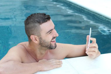 Yüzme havuzunda kameraya bakan yakışıklı genç adamın yakın plan portresi.