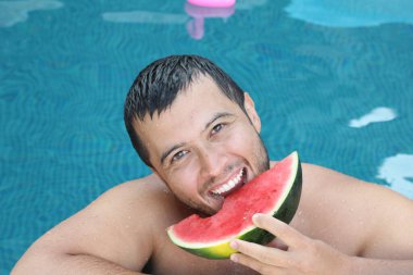 Yüzme havuzunda kameraya bakan yakışıklı genç adamın yakın plan portresi.