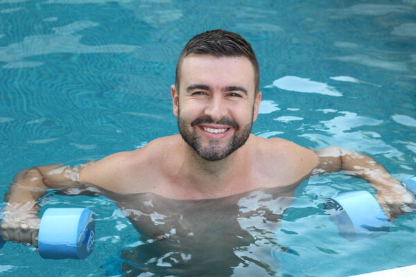 close-up portrait of handsome young man swimming with inflatable dumbbells  in swimming pool