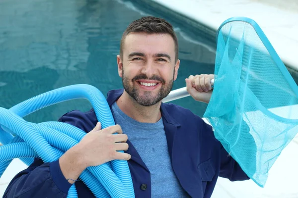 Yüzme havuzunun yanında yüzen ve havuz temizleme konseptine bakan üniformalı yakışıklı genç adamın yakın plan portresi.