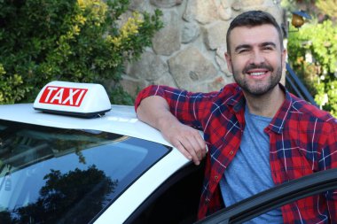 Yakışıklı genç bir taksi şoförünün arabasıyla portresi.