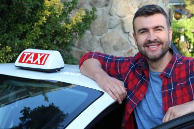 Yakışıklı genç bir taksi şoförünün arabasıyla portresi.