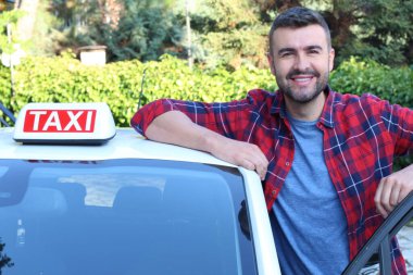 Yakışıklı genç bir taksi şoförünün arabasıyla portresi.