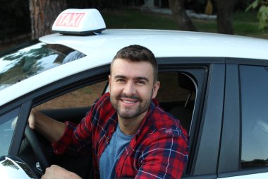 Yakışıklı genç bir taksi şoförünün arabasıyla portresi.