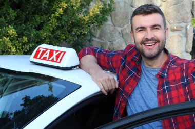 Yakışıklı genç bir taksi şoförünün arabasıyla portresi.