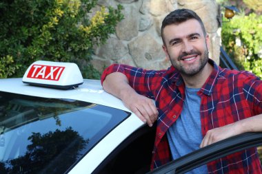 Yakışıklı genç bir taksi şoförünün arabasıyla portresi.