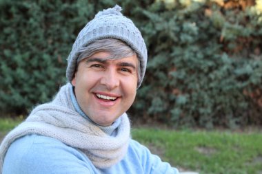 Parkta kalın giysiler içinde yakışıklı olgun bir adamın yakın plan portresi.