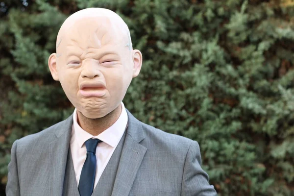 close-up portrait of businessman in crybaby mask in park