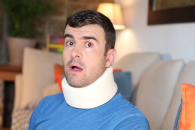 Boynu yaralanmış yakışıklı bir gencin yakın plan portresi evde sabitlenmiş bir şekilde oturuyor. 