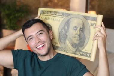 Elinde 100 dolarlık banknot tutan yakışıklı bir gencin yakın plan portresi.