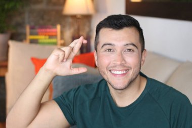 Evde çapraz parmaklı yakışıklı bir gencin yakın plan portresi.