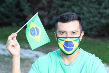 Koruma maskesi ve Brezilya bayrağı takmış genç bir adamın portresi.