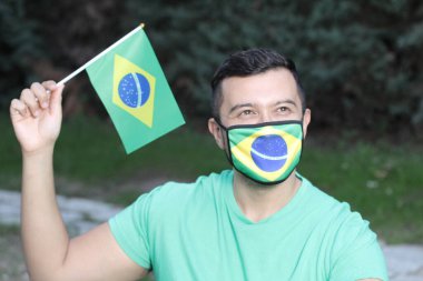Koruma maskesi ve Brezilya bayrağı takmış genç bir adamın portresi.