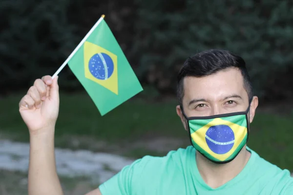 自然界に保護マスクとブラジルの旗を持つ若い男の肖像画 — ストック写真