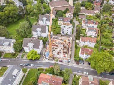 İsviçre 'nin yerleşim alanındaki büyük vinçli inşaat alanının havadan görüntüsü.