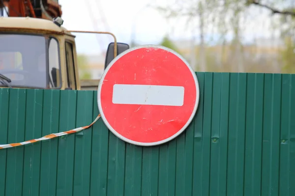 Cartello stradale rotondo rosso con striscia bianca che vieta il movimento sulla recinzione verde di lamiera di ferro. Non entrate. concetto di proibizione, vicolo cieco, disperazione e arresto — Foto Stock