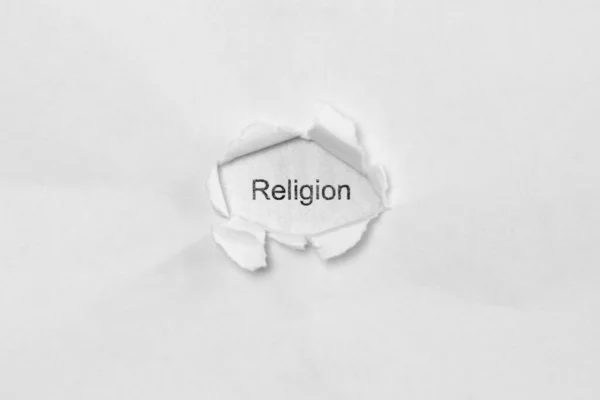 Word religion på vit isolerad bakgrund genom såret hålet i papperet. — Stockfoto