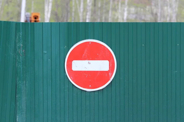 Red round road sign with white stripe prohibiting movement on the green fence of sheet iron. Do not enter. concept of prohibition, dead end, hopelessness and stop — Stock Photo, Image