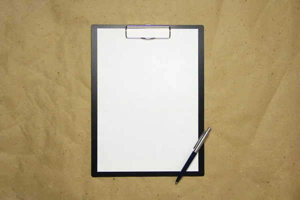 Tableta s bílým listem formátu A4 na béžovém řemeslném papíru. — Stock fotografie
