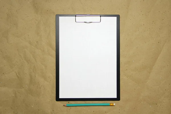 A tablet with a white sheet of A4 format on a beige craft paper. — Stock Photo, Image