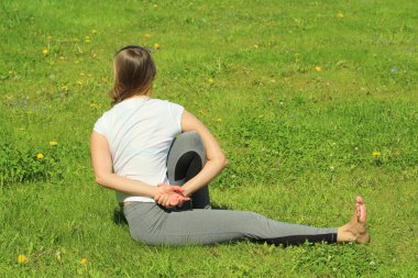 Avrupa görünümlü genç bir kadın yaz doğasında yoga yapıyor. Marichiasana 'da oturan kadın web ve yazı için yüksek kaliteli fotoğraf ve metin ve tasarım için boş alan ile.