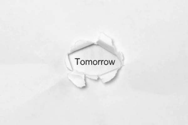 Word Tomorrow on white isolated background through the wound hole in the paper. — Stock Photo, Image