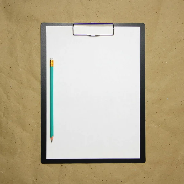 Une tablette avec une feuille blanche de format A4 sur un papier artisanal beige. — Photo