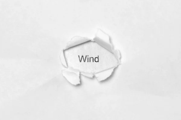 Woord Wind op witte geïsoleerde achtergrond door het wond gat in het papier. — Stockfoto