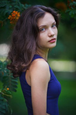 Girl in a blue dress walks in the park