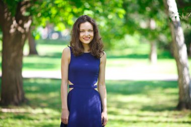 Girl in a blue dress walks in the park