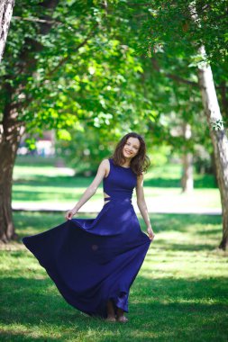 Girl in a blue dress walks in the park