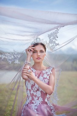 Kraliçe. Dağların arka planında bir kraliçe suretinde bir kız.