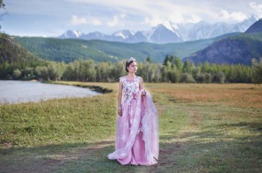 Kraliçe. Dağların arka planında bir kraliçe suretinde bir kız.